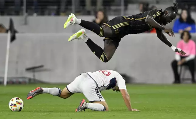 CORRECTS TO SECOND HALF FROM FIRST HALF - Los Angeles FC forward Kei Kamara, top, flies over Vancouver Whitecaps midfielder Sebastian Berhalter (16) on a tripping foul during the second half of the first match of an MLS Cup playoffs opening round in Los Angeles, Sunday, Oct. 27, 2024. (AP Photo/Alex Gallardo)