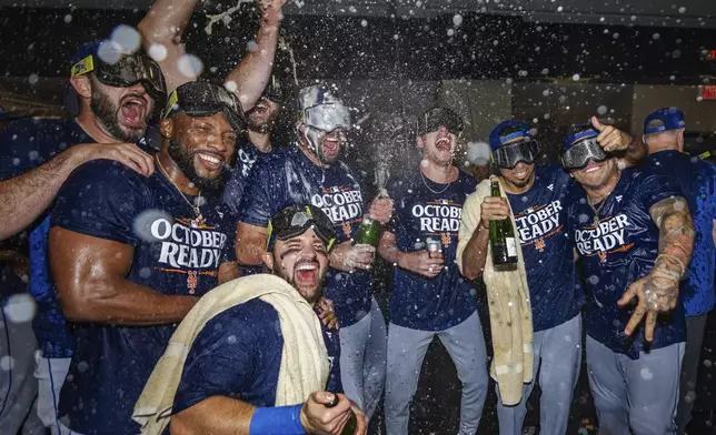 CORRECTS BY REMOVING WILD CARD REFERENCE - The New York Mets celebrate in the locker room after clinching a playoff berth with a victory in the first game of a doubleheader against the Atlanta Braves, Monday, Sept. 30, 2024, in Atlanta. (AP Photo/Jason Allen)