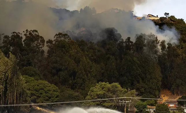 An air tanker drops retardant on a grass fire burning above Interstate 580 in Oakland, Calif., Friday, Oct. 18, 2024. (AP Photo/Noah Berger)