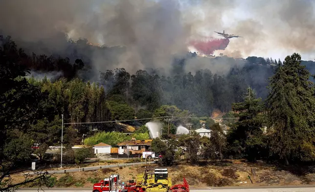 An air tanker drops retardant on a grass fire burning above Interstate 580 in Oakland, Calif., Friday, Oct. 18, 2024. (AP Photo/Noah Berger)