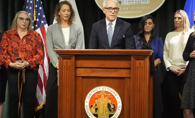 Los Angeles County District Attorney George Gascon, right, flanked by Menedez family members talks during a news conference at the Hall of Justice on Thursday, Oct. 24, 2024, in Los Angeles. (AP Photo/Damian Dovarganes)