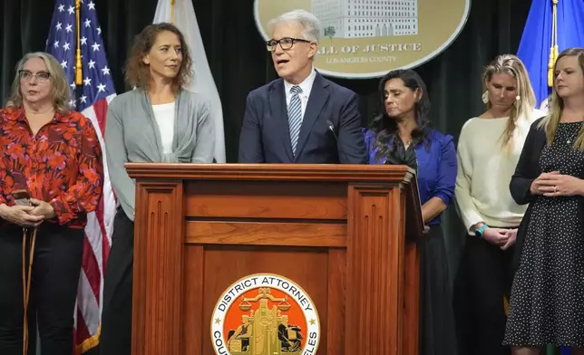 Los Angeles County District Attorney George Gascon, right, flanked by Menedez family members talks during a news conference at the Hall of Justice on Thursday, Oct. 24, 2024, in Los Angeles. (AP Photo/Damian Dovarganes)