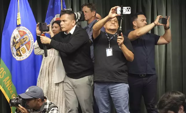 Members of the media take photos during a news conference about the Menedez brothers held by Los Angeles County District Attorney George Gascon, Thursday, Oct. 24, 2024, in Los Angeles. (AP Photo/Damian Dovarganes)