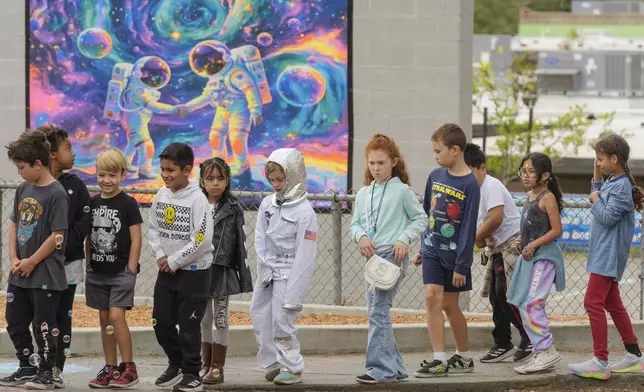 Santiago STEAM Magnet Elementary School students arrived dressed with space themed clothing at a ceremony to plant a small Giant Sequoia tree from NASA's Artemis I Mission's tree seeds that traveled around the moon twice, after the school was honored in the spring of 2024 to become NASA Moon Tree Stewards in Lake Forest, Calif., on Monday, Oct. 14, 2024. (AP Photo/Damian Dovarganes)