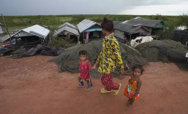 Children walk past a floating village, by the Tonle Sap in Kampong Chhnang province, Cambodia, Thursday, Aug. 1, 2024, (AP Photo/Heng Sinith)