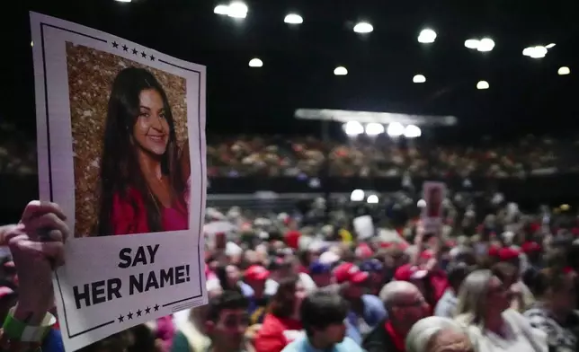 FILE - A supporter holds a sign with a photo of Laken Riley before Republican presidential candidate former President Donald Trump speaks at a campaign rally, Saturday, March 9, 2024, in Rome Ga. (AP Photo/Mike Stewart, File)