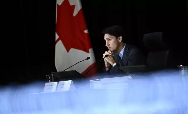 Prime Minister Justin Trudeau is seen past a TV screen showing a live transcription as he appears as a witness at the Foreign Interference Commission in Ottawa, Wednesday, Oct. 16, 2024. (Justin Tang/The Canadian Press via AP)