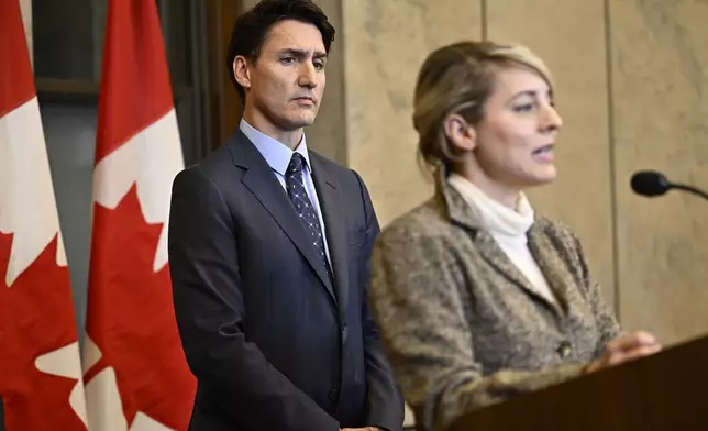 Prime Minister Justin Trudeau listens as Minister of Foreign Affairs Melanie Joly speaks at a news conference on the investigative efforts related to violent criminal activity occurring in Canada with connections to India, on Parliament Hill in Ottawa, on Monday, Oct. 14, 2024. (Justin Tang/The Canadian Press via AP)