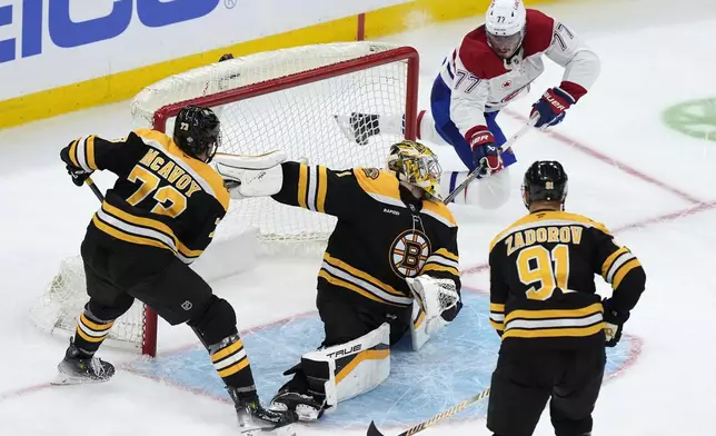 Boston Bruins' Jeremy Swayman (1) blocks a shot by Montreal Canadiens' Kirby Dach (77) as Charlie McAvoy (73) and Nikita Zadorov (91) defend during the third period of an NHL hockey game, Thursday, Oct. 10, 2024, in Boston. (AP Photo/Michael Dwyer)