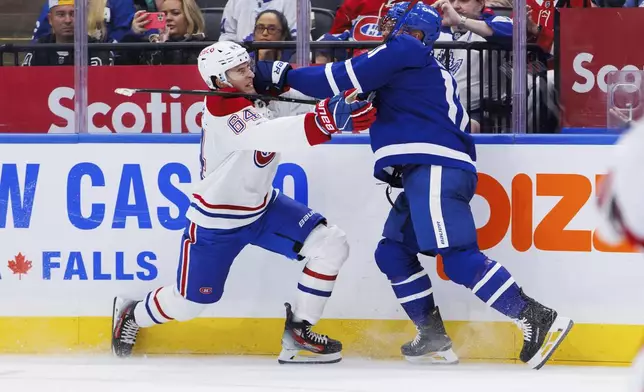 Montreal Canadiens' David Reinbacher (64) gets hit in the face by Toronto Maple Leafs' Max Domi (11) as they skate along the boards during the second period of a preseason NHL hockey game in Toronto, Thursday, Sept. 26, 2024. (Cole Burston/The Canadian Press via AP)