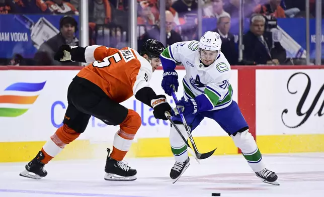 Vancouver Canucks' Nils Hoglander, right, skates past Philadelphia Flyers' Egor Zamula during the first period of an NHL hockey game, Saturday, Oct. 19, 2024, in Philadelphia. (AP Photo/Derik Hamilton)