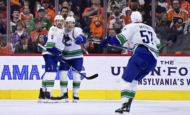 Vancouver Canucks' Brock Boeser, center, celebrates his goal with J.T. Miller (9) and Tyler Myers (57) during the second period of an NHL hockey game against the Philadelphia Flyers, Saturday, Oct. 19, 2024, in Philadelphia. (AP Photo/Derik Hamilton)