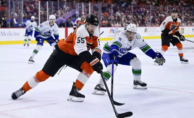 Philadelphia Flyers' Rasmus Ristolainen, left, plays the puck past Vancouver Canucks' Nils Hoglander (21) during the first period of an NHL hockey game, Saturday, Oct. 19, 2024, in Philadelphia. (AP Photo/Derik Hamilton)