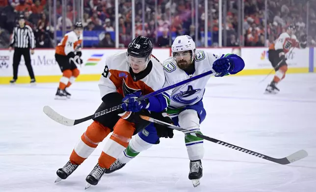 Philadelphia Flyers' Matvei Michkov, left, and Vancouver Canucks' Conor Garland (8) race for the puck during the second period of an NHL hockey game, Saturday, Oct. 19, 2024, in Philadelphia. (AP Photo/Derik Hamilton)