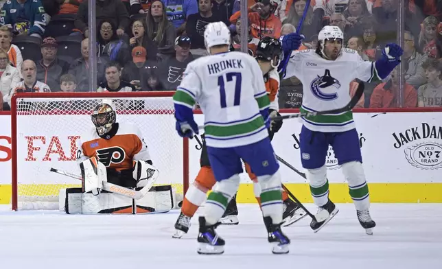 Philadelphia Flyers goaltender Samuel Ersson, left, reacts after giving up a goal to Vancouver Canucks' Kiefer Sherwood, right, during the second period of an NHL hockey game, Saturday, Oct. 19, 2024, in Philadelphia. (AP Photo/Derik Hamilton)