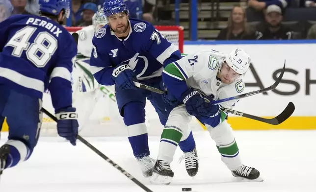 Tampa Bay Lightning left wing Conor Sheary (73) hooks Vancouver Canucks left wing Nils Hoglander (21) for a penalty during the first period of an NHL hockey game Tuesday, Oct. 15, 2024, in Tampa, Fla. (AP Photo/Chris O'Meara)