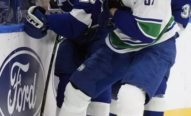 Vancouver Canucks defenseman Tyler Myers (57) ties up the puck in front of Tampa Bay Lightning left wing Nicholas Paul (20) and left wing Brandon Hagel (38) during the second period of an NHL hockey game Tuesday, Oct. 15, 2024, in Tampa, Fla. (AP Photo/Chris O'Meara)