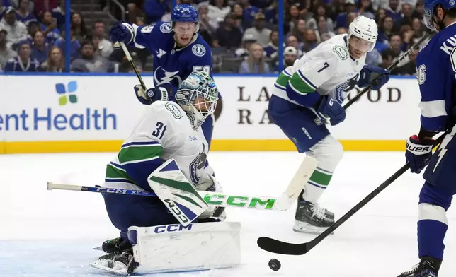 Vancouver Canucks goaltender Arturs Silovs (31) stops a shot by Tampa Bay Lightning right wing Nikita Kucherov (86) as center Jake Guentzel (59) and defenseman Carson Soucy (7) look for a rebound during the second period of an NHL hockey game Tuesday, Oct. 15, 2024, in Tampa, Fla. (AP Photo/Chris O'Meara)