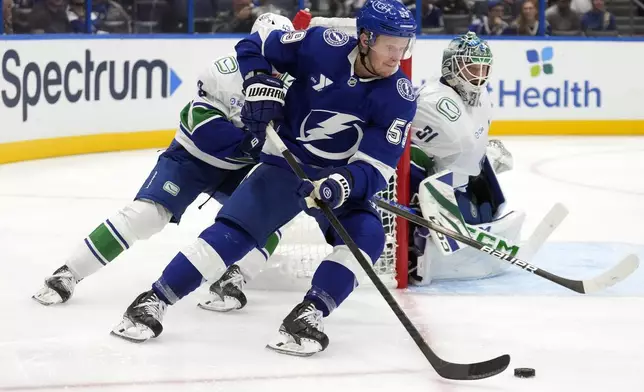 Tampa Bay Lightning center Jake Guentzel (59) works around Vancouver Canucks defenseman Quinn Hughes (43) and goaltender Arturs Silovs (31) during the second period of an NHL hockey game Tuesday, Oct. 15, 2024, in Tampa, Fla. (AP Photo/Chris O'Meara)