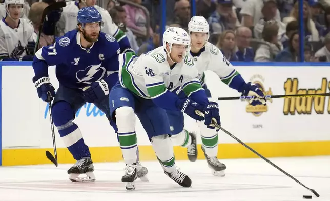 Vancouver Canucks center Elias Pettersson (40) moves the puck around Tampa Bay Lightning defenseman Victor Hedman (77) during the first period of an NHL hockey game Tuesday, Oct. 15, 2024, in Tampa, Fla. (AP Photo/Chris O'Meara)