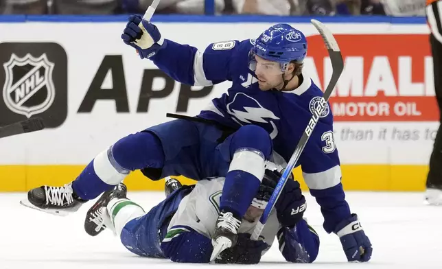 Tampa Bay Lightning left wing Brandon Hagel (38) takes down Vancouver Canucks left wing Jake DeBrusk (74) during the first period of an NHL hockey game Tuesday, Oct. 15, 2024, in Tampa, Fla. (AP Photo/Chris O'Meara)