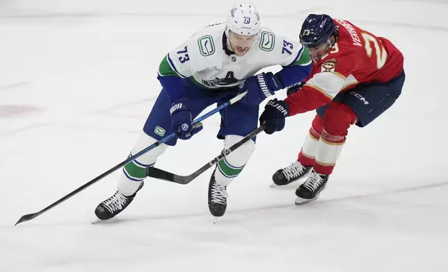 Vancouver Canucks defenseman Vincent Desharnais (73) and Florida Panthers center Carter Verhaeghe (23) battle for the puck during the first period of an NHL hockey game, Thursday, Oct. 17, 2024, in Sunrise, Fla. (AP Photo/Wilfredo Lee)