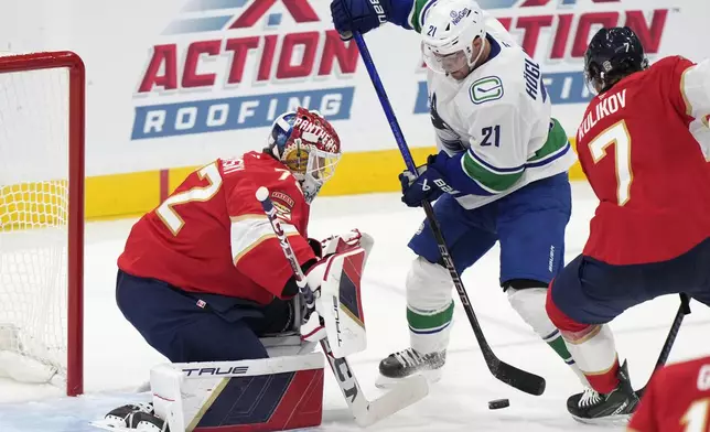 Vancouver Canucks left wing Nils Hoglander (21) attempts a shot at Florida Panthers goaltender Sergei Bobrovsky (72) and defenseman Dmitry Kulikov (7) during the second period of an NHL hockey game, Thursday, Oct. 17, 2024, in Sunrise, Fla. (AP Photo/Wilfredo Lee)