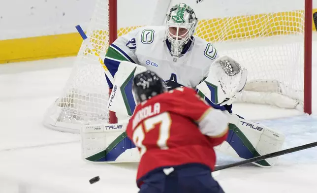 Florida Panthers defenseman Niko Mikkola (77) attempts a shot against Vancouver Canucks goaltender Kevin Lankinen (32) during the first period of an NHL hockey game, Thursday, Oct. 17, 2024, in Sunrise, Fla. (AP Photo/Wilfredo Lee)