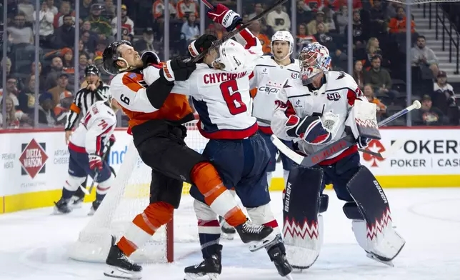 Philadelphia Flyers' Travis Sanheim, left, gets into it with Washington Capitals' Jakob Chychrun, center, after Sanheim took a swipe at the puck that Charlie Lindgren, right, had during the second period of an NHL hockey game, Tuesday, Oct. 22, 2024, in Philadelphia. (AP Photo/Chris Szagola)