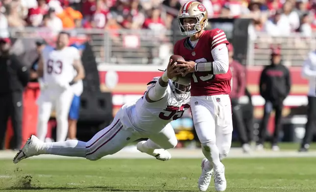 San Francisco 49ers quarterback Brock Purdy, right, scrambles away from Arizona Cardinals defensive tackle Dante Stills during the second half of an NFL football game in Santa Clara, Calif., Sunday, Oct. 6, 2024. (AP Photo/Godofredo A. Vásquez)