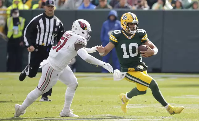 Green Bay Packers quarterback Jordan Love (10) is chased by Arizona Cardinals linebacker Krys Barnes (51) during the second half of an NFL football game, Sunday, Oct. 13, 2024, in Green Bay. (AP Photo/Mike Roemer)