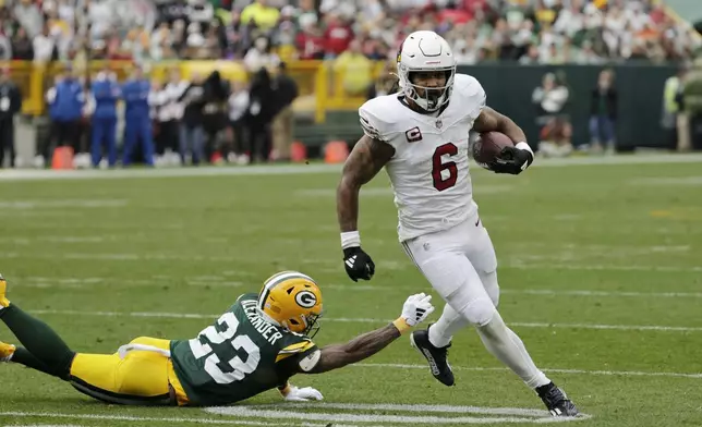 Arizona Cardinals running back James Conner (6) pulls away form Green Bay Packers cornerback Jaire Alexander (23) during the first half of an NFL football game, Sunday, Oct. 13, 2024, in Green Bay. (AP Photo/Mike Roemer)