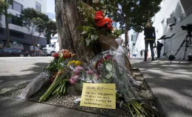 FILE - Flowers sit at a tree in front of the building where a technology executive was fatally stabbed outside of in San Francisco, April 6, 2023. (AP Photo/Jeff Chiu, File)