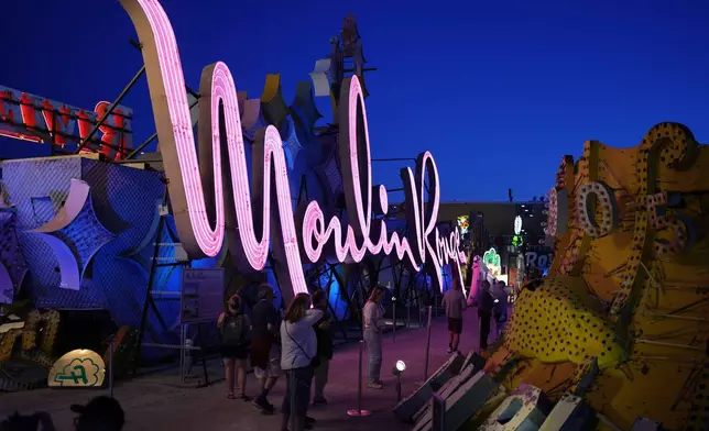 People look at signs from defunct Las Vegas casinos on display at the Neon Museum, Wednesday, April 3, 2024, in Las Vegas. (AP Photo/John Locher)