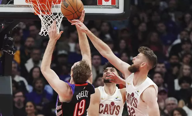 Toronto Raptors' Jakob Poeltl (19) is fouled by Cleveland Cavaliers' Dean Wade (32) as Cavaliers' Ty Jerome (2) looks on during the first half of an NBA basketball game, Wednesday, Oct. 23, 2024 in Toronto. (Frank Gunn/The Canadian Press via AP)