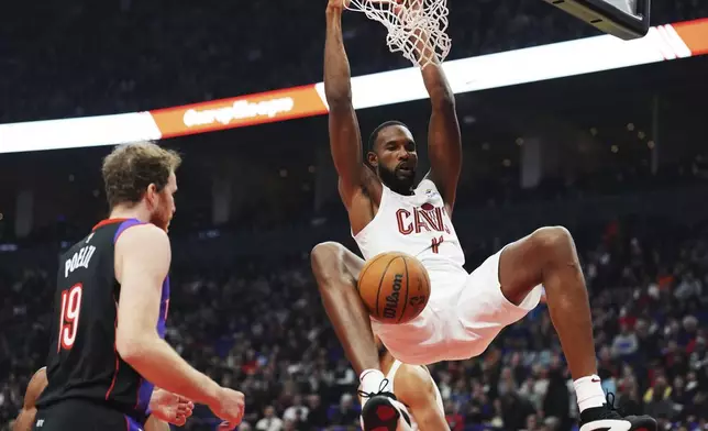 Cleveland Cavaliers' Evan Mobley (4) dunks as Toronto Raptors' Jakob Poeltl (19) looks on during the first half of an NBA basketball game, Wednesday, Oct. 23, 2024 in Toronto. (Frank Gunn/The Canadian Press via AP)