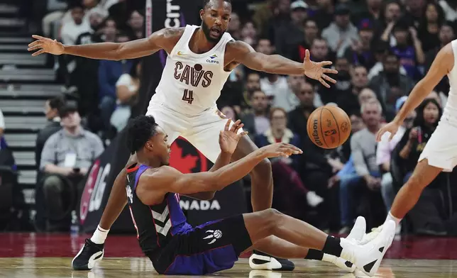 Toronto Raptors' Scottie Barnes, bottom, passes as Cleveland Cavaliers' Evan Mobley (4) defends during the first half of an NBA basketball game, Wednesday, Oct. 23, 2024 in Toronto. (Frank Gunn/The Canadian Press via AP)