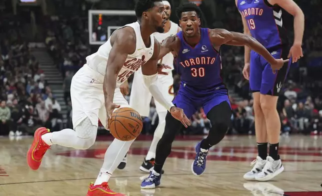 Cleveland Cavaliers' Donovan Mitchell (45) drives past Toronto Raptors' Ochai Agbaji (30) during the first half of an NBA basketball game, Wednesday, Oct. 23, 2024 in Toronto. (Frank Gunn/The Canadian Press via AP)