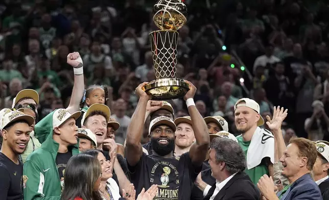 FILE - Boston Celtics guard Jaylen Brown, center, holds up the Larry O'Brien Championship Trophy as he celebrates with the team after they won the NBA basketball championship with a Game 5 victory over the Dallas Mavericks, Monday, June 17, 2024, in Boston. (AP Photo/Charles Krupa, FIle)