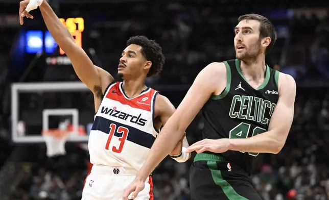 Washington Wizards guard Jordan Poole (13) watches his 3-point basket against Boston Celtics center Luke Kornet, right, during the first half of an NBA basketball game Thursday, Oct. 24, 2024, in Washington. (AP Photo/John McDonnell)