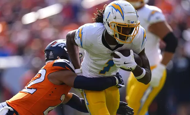 Los Angeles Chargers wide receiver Quentin Johnston (1) runs with the football as Denver Broncos safety Brandon Jones (22) tries to tackle during the first half of an NFL football game, Sunday, Oct. 13, 2024, in Denver. (AP Photo/David Zalubowski)