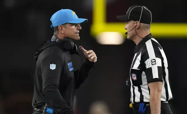 Los Angeles Chargers head coach Jim Harbaugh, left, talks with down judge Dana McKenzie, right, during the first half of an NFL football game against the Arizona Cardinals, Monday, Oct. 21, 2024, in Glendale Ariz. (AP Photo/Matt York)