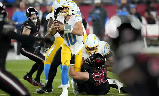 Los Angeles Chargers quarterback Justin Herbert (10) is sacked by Arizona Cardinals defensive end Ben Stille (90) during the first half of an NFL football game, Monday, Oct. 21, 2024, in Glendale Ariz. (AP Photo/Ross D. Franklin)