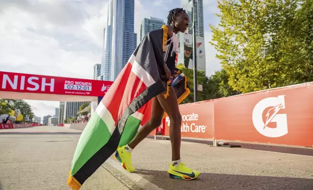 Ruth Chepngetich, from Kenya, reacts after crossing the finish line of the Chicago Marathon to win the women's professional division and break the women's marathon world record in Grant Park on Sunday, Oct. 13, 2024. (Tess Crowley/Chicago Tribune via AP)