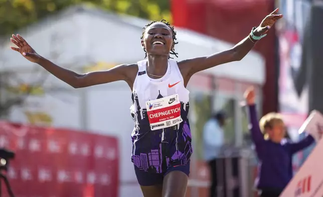 Ruth Chepngetich, from Kenya, crosses the finish line of the Chicago Marathon to win the women's professional division and break the women's marathon world record in Grant Park on Sunday, Oct. 13, 2024. (Tess Crowley/Chicago Tribune via AP)