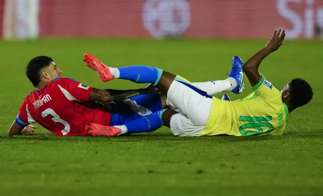 Chile's Guillermo Maripan, left, and Brazil's Abner fall after colliding during a FIFA World Cup 2026 qualifying soccer match at the National Stadium in Santiago, Chile, Thursday, Oct. 10, 2024. (AP Photo/Esteban Felix)