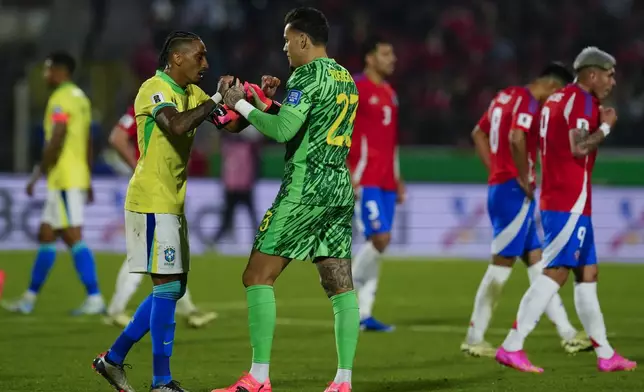 Brazil's goalkeeper Ederson, center, celebrates with teammate Raphinha their team's 2-1 victory over Chile in a FIFA World Cup 2026 qualifying soccer match at the National Stadium in Santiago, Chile, Thursday, Oct. 10, 2024. (AP Photo/Esteban Felix)