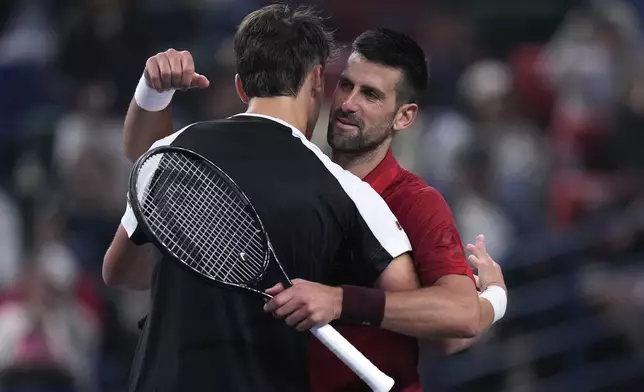 Novak Djokovic of Serbia, right, hugs with Jake Mensik of the Czech Republic after winning in their men's singles quarterfinals match of the Shanghai Masters tennis tournament at Qizhong Forest Sports City Tennis Center in Shanghai, China, Friday, Oct. 11, 2024. (AP Photo/Andy Wong)