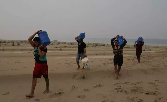 FILE - Residents transport drinking water from Humaita to the Paraizinho community, along a dry part of the Madeira River, a tributary of the Amazon River, amid a drought, Amazonas state, Brazil, Sep. 8, 2024. (AP Photo/Edmar Barros, File)