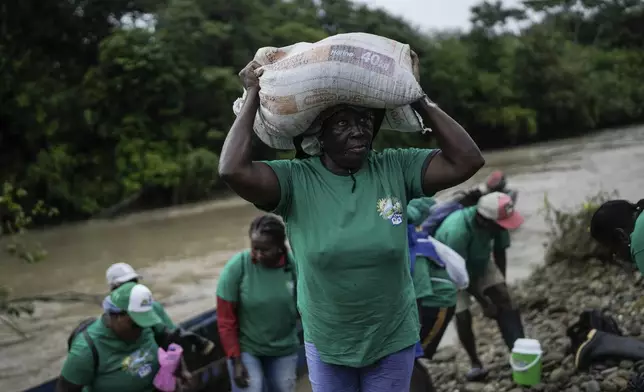 A woman, part of Asociacion Nuestra Casa Comun, or Our Community House Association, carries fertilizer to help reforest an area destroyed by illegal mining, near Paimado, Colombia, Tuesday, Sept. 24, 2024. (AP Photo/Ivan Valencia)